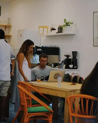 a woman standing next to a man sitting at a table with a laptop at Jaca Hostel Funchal in Funchal