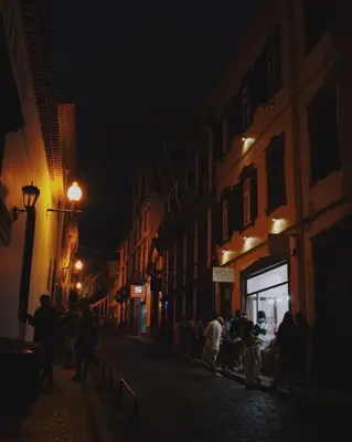 a group of people walking down a street at night at Jaca Hostel Funchal in Funchal