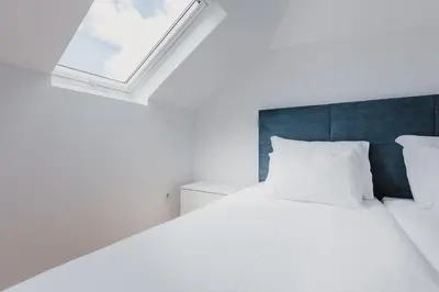 a bedroom with a white bed with a window at Jaca Hostel Funchal in Funchal