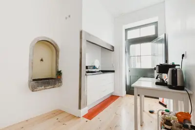 a kitchen with white walls and a table and a mirror at Jaca Hostel Funchal in Funchal