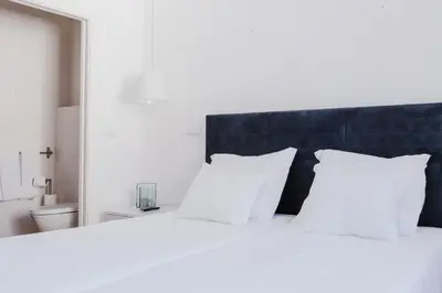 a white bed with white pillows and a blue headboard at Jaca Hostel Funchal in Funchal