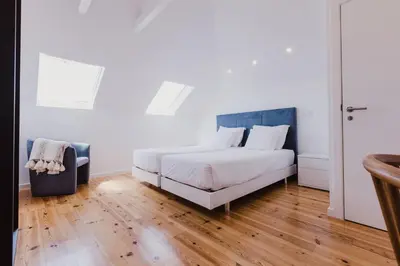 a bedroom with a white bed and a wooden floor at Jaca Hostel Funchal in Funchal