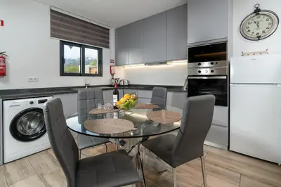 a kitchen with a glass table and chairs and a dishwasher at Casa Zé, in Arco da Calheta