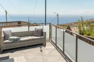 a couch on a balcony with a view of the ocean at Casa Zé, in Arco da Calheta