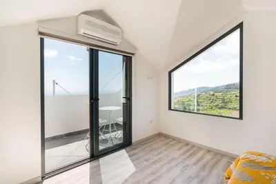 a white room with a large window and a table at Casa Zé, in Arco da Calheta