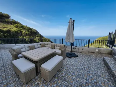 a patio with a table and chairs and an umbrella at Casa Leão de Ouro by LovelyStay in São Jorge