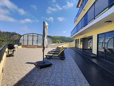 a building with benches and an umbrella on a patio at Casa Leão de Ouro by LovelyStay in São Jorge