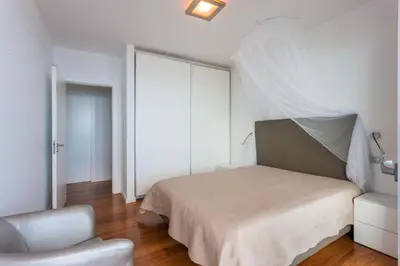 a white bedroom with a bed and a chair at Casa Martinhos by LovelyStay in Caniço
