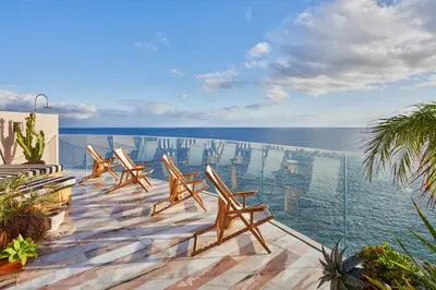 a woman sitting by a pool looking out at the water at Okulus Madeira in Funchal