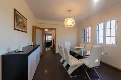 a dining room with a black table and white chairs at Cristina Grand in São Vicente