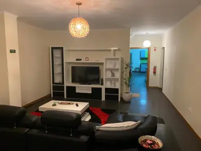 a living room with a couch and a tv at Cristina Grand in São Vicente