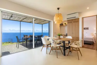a dining room and living room with a view of the ocean at Villa Flora - Nature & Tranquility - Heated pool optional in Jardim do Mar