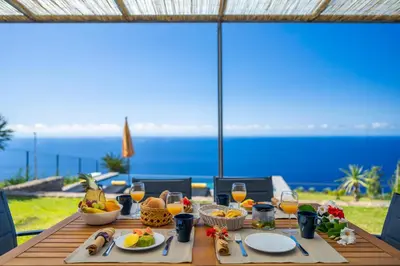 a table with food and a view of the ocean at Cantinho da Natureza - Nature & Tranquility - Heated pool optional in Jardim do Mar