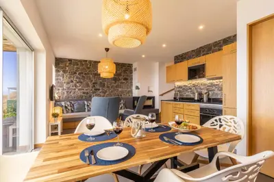 a kitchen and dining room with a wooden table and chairs at Cantinho da Natureza - Nature & Tranquility - Heated pool optional in Jardim do Mar