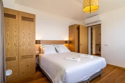 a bedroom with a large white bed and wooden cabinets at Cantinho da Natureza - Nature & Tranquility - Heated pool optional in Jardim do Mar