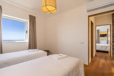 two beds in a room with a window at Cantinho da Natureza - Nature & Tranquility - Heated pool optional in Jardim do Mar
