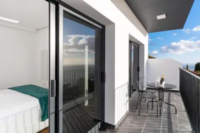 a bedroom with a balcony with a bed and a table at Relax View in Funchal