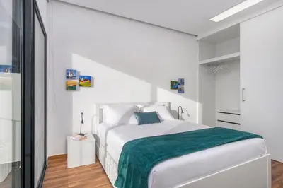 a white bedroom with a large bed with a green blanket at Relax View in Funchal