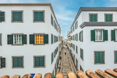 an alley between two buildings with green shutters at Ribeira das Casas by Homie in Funchal