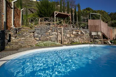 a large blue swimming pool in front of a stone wall at Ga281 in Funchal