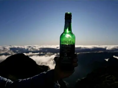 a person holding a bottle of beer on top of a mountain at O pomar - A quiet SUNNY place with amazing SEA views in Paul do Mar