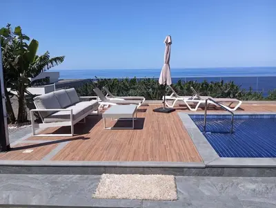 a patio with chairs and an umbrella and a pool at O pomar - A quiet SUNNY place with amazing SEA views in Paul do Mar