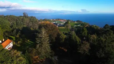 an aerial view of a house on a hill next to the ocean at Quinta Das Faias in Camacha