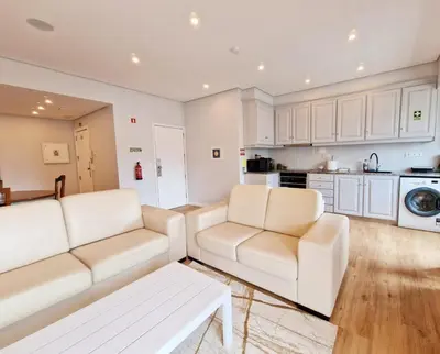 a living room with two white couches and a kitchen at Princesa Madeira in Funchal