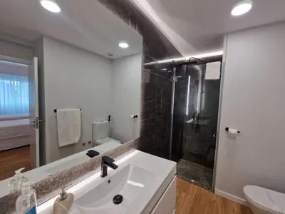 a white bathroom with a sink and a shower at Princesa Madeira in Funchal