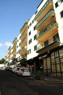 a row of apartment buildings on a street with parked cars at Princesa Madeira in Funchal
