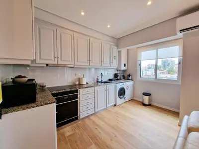 a kitchen with white cabinets and a washer and dryer at Princesa Madeira in Funchal
