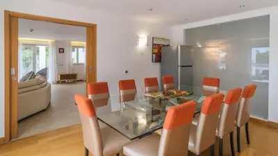 a dining room with a glass table and orange chairs at Casa Monte Cristo Too in Lagos