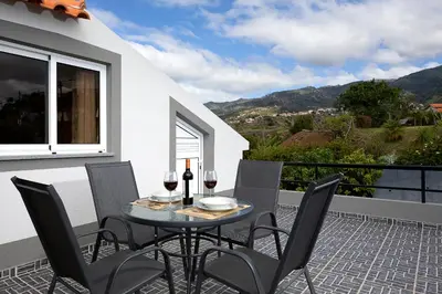 a table with two glasses of wine on a balcony at Martinho Apartment View in Arco da Calheta