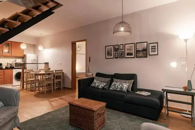 a living room with a black couch and a kitchen at Ocean View in Ponta Delgada