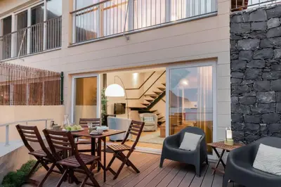 a patio with a wooden table and chairs at Ocean View in Ponta Delgada