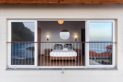 a balcony with a view of a bedroom and the ocean at Ocean View in Ponta Delgada
