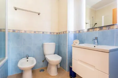 a blue tiled bathroom with a toilet and a sink at Lovely 2 bedroom apartment including pool, stunning ocean views & beach closeby in Luz