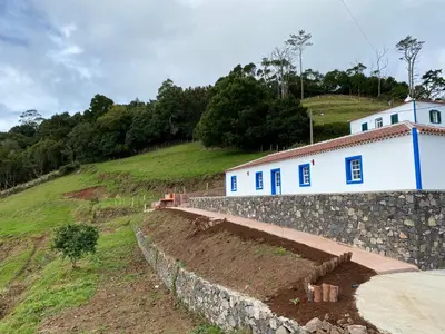 a stone retaining wall next to a white building at Casa da Bisa - Santa Maria - Açores in Santa Bárbara