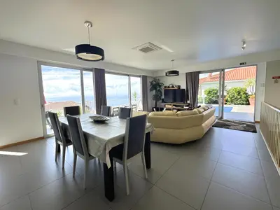 a balcony with a table and chairs and an umbrella at Blue Villa in Arco da Calheta