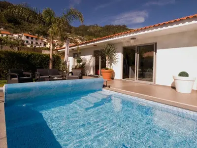 a swimming pool in front of a house at Blue Villa in Arco da Calheta
