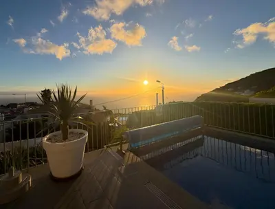 a bedroom with two beds with red sheets and a window at Blue Villa in Arco da Calheta