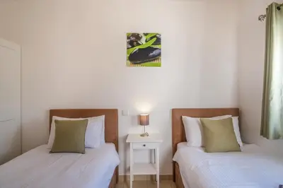 a bedroom with two beds and a table with a lamp at Casa Monte Cristo IV in Lagos