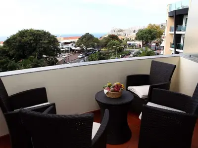 a balcony with chairs and a table with a bowl of fruit at Charming Lido Flat I in Funchal