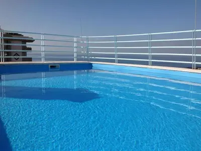 a swimming pool with a fence and blue water at Charming Lido Flat I in Funchal