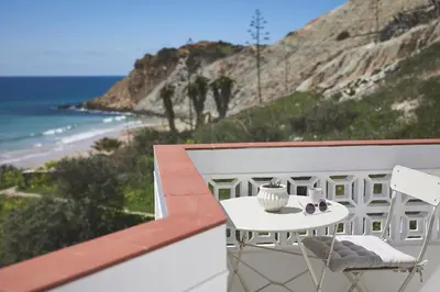 a table and chairs on a balcony with a beach at Casas Sul in Burgau
