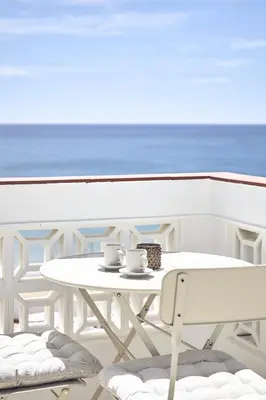 a white table and chairs on a balcony with the ocean at Casas Sul in Burgau