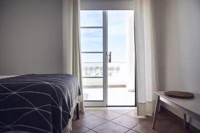 a bedroom with a bed and a table and a window at Casas Sul in Burgau