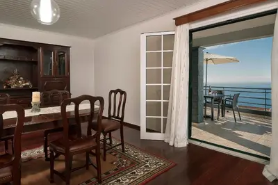 a dining room with a table and a view of the ocean at Welcome home, with a fantastic view, sunrise & sunsets in Estreito da Calheta