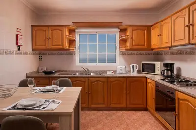 a kitchen with wooden cabinets and a table and a window at Welcome home, with a fantastic view, sunrise & sunsets in Estreito da Calheta