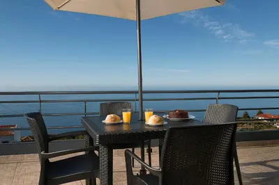 a table with food and drinks on top of a balcony at Welcome home, with a fantastic view, sunrise & sunsets in Estreito da Calheta